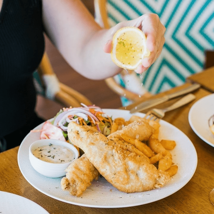 Squeezing lemon over fish and chips