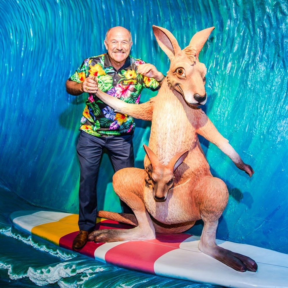 Wallie Lewis standing with surfing kangaroo statue inside the Banana Bender Pub